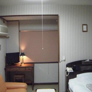 a room with a bed and a desk with a television at Ryokan Seifuso in Ōmuta