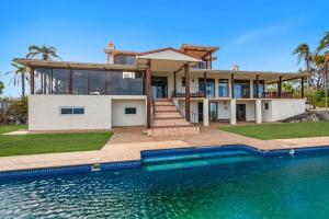 a house with a swimming pool in front of a house at Casa Del Rio - LJHooker Yamba in Ashby