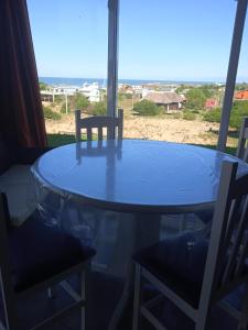 a glass table and chairs with a view of the ocean at Estrella de la viuda in Punta Del Diablo