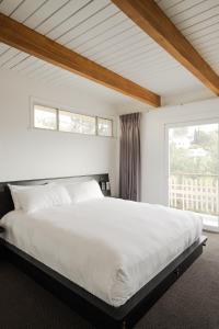 a bedroom with a large white bed with two windows at Hollywood Hills Hotel in Los Angeles