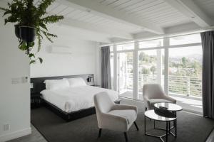a bedroom with a bed and chairs and a large window at Hollywood Hills Hotel in Los Angeles