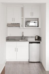 a white kitchen with a sink and a microwave at Hollywood Hills Hotel in Los Angeles