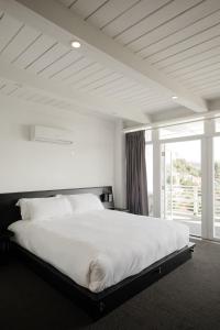 a white bedroom with a large bed and a window at Hollywood Hills Hotel in Los Angeles