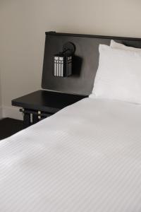 a white bed with a black night stand next to it at Hollywood Hills Hotel in Los Angeles