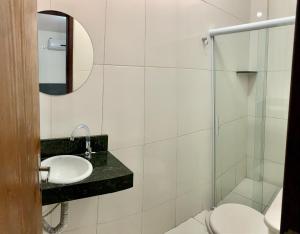 a bathroom with a sink and a toilet and a mirror at Pousada Ô de Casa in Piranhas