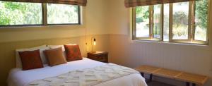 a bedroom with a white bed and two windows at Burn Cottage Retreat in Cromwell