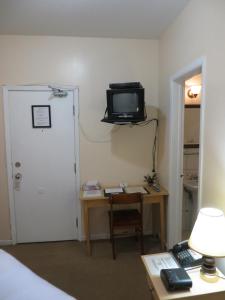 a room with a desk and a tv on the wall at Victoria's Mansion Guest House in Toronto