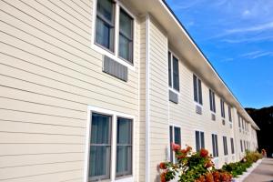 una casa con revestimiento blanco y ventanas en Holly Tree Resort, a VRI resort en West Yarmouth