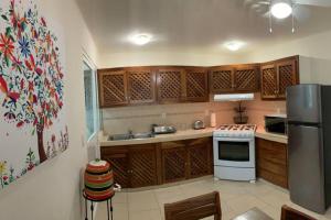 Una cocina con gabinetes de madera y refrigerador. en El Colorín, a condo in the heart of Huatulco, en Santa Cruz Huatulco
