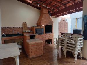 y cocina con horno de ladrillo, mesas y sillas. en Casa Azul no Centro Ilha Comprida, en Ilha Comprida