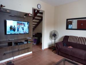 a living room with a couch and a flat screen tv at Casa Azul no Centro Ilha Comprida in Ilha Comprida