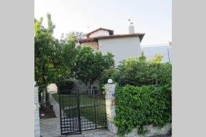 um portão preto em frente a um edifício branco em Τraditional fully detached villa on a luxurious hillock of Thessaloniki with its own garden also for family & wedding gatherings for 10 to 25 people only 15 minutes from airport em Tessalônica