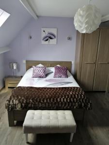 een slaapkamer met een groot bed met paarse kussens bij Chambres d'Hotes La Maison Neuve in Saint-Loup