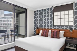 a bedroom with a large bed and a balcony at Mantra Sydney Central in Sydney