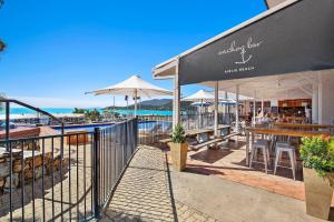 a restaurant with tables and umbrellas next to the beach at OCEAN VIEWS 10 in Airlie Beach