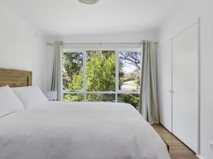 a white bedroom with a large window at Woodlands Retreat Rye in Rye