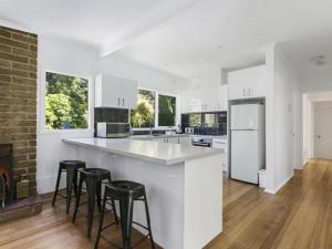 a kitchen with white cabinets and black bar stools at Woodlands Retreat Rye in Rye
