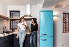 two women standing in a kitchen next to a blue refrigerator at Perouse Randwick by Sydney Lodges in Sydney