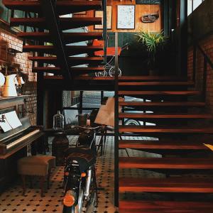 uma escada num quarto com um piano e uma bicicleta em Dream Factory Hotel em Udon Thani