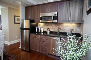 a kitchen with wooden cabinets and a stainless steel refrigerator at Norwalk Inn & Conference Center in Norwalk