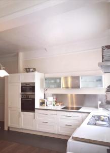 a kitchen with white cabinets and a stove top oven at Les Chambres des Barques in Narbonne