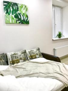 een slaapkamer met een bed met kussens en een schilderij aan de muur bij Новые апартаменты в ЖК БАРСКИЙ in Yakushintsy