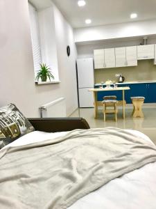 ein Schlafzimmer mit einem Bett und eine Küche mit einem Tisch in der Unterkunft Новые апартаменты в ЖК БАРСКИЙ in Yakushintsy