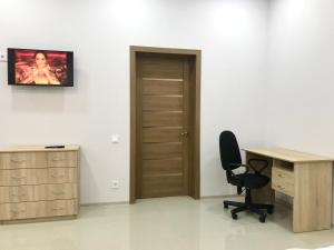 um escritório com uma secretária, uma cadeira e uma porta de madeira em Новые апартаменты в ЖК БАРСКИЙ em Yakushintsy