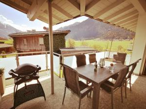 un patio con mesa, sillas y parrilla en Ferienwohnungen Strass im Zillertal, en Strass im Zillertal