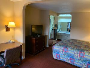 Habitación de hotel con cama, escritorio y TV. en Pleasanton Executive Inn en Pleasanton