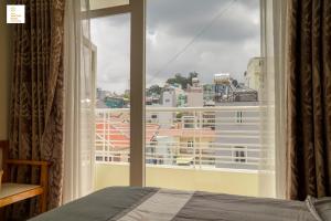 une chambre avec une fenêtre donnant sur un immeuble dans l'établissement New Sun Hotel Đà Lạt, à Đà Lạt