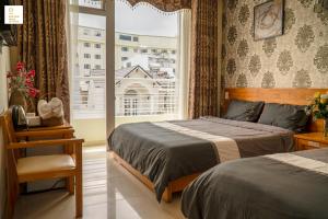 une chambre avec deux lits et une fenêtre dans l'établissement New Sun Hotel Đà Lạt, à Đà Lạt 90 autres photos