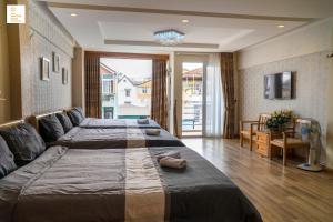 une chambre d'hôtel avec deux lits et une télévision dans l'établissement New Sun Hotel Đà Lạt, à Đà Lạt