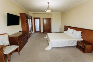 a bedroom with a bed and a tv and a chair at Stanislaviv in Ivano-Frankivsʼk