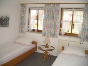 Un dormitorio con dos camas y una mesa y ventanas. en Ferienwohnung Hinterstoißer, en Berchtesgaden