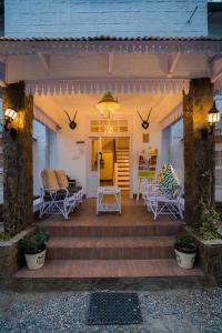 um alpendre com cadeiras e um sofá numa casa em Bhikampur Lodge By Howard em Nainital