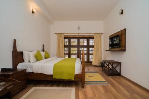 um quarto com uma cama grande e uma televisão em Bhikampur Lodge By Howard em Nainital
