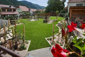 ogród z trawnikiem z fontanną i czerwonymi kwiatami w obiekcie Hotel-Restaurant Kirchenwirt w mieście Weissenkirchen in der Wachau