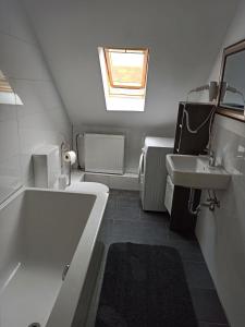 un bagno bianco con vasca e lavandino di Apartments zum stillen Winkel a Niederbreitbach