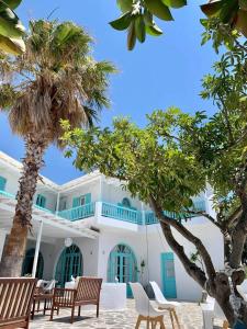 a white building with blue windows and palm trees at Aliki Panorama Rooms in Aliki