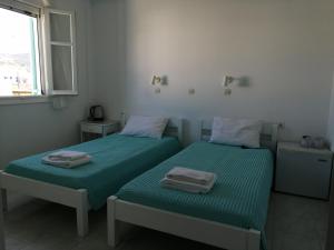 two beds in a white room with towels on them at Aliki Panorama Rooms in Aliki