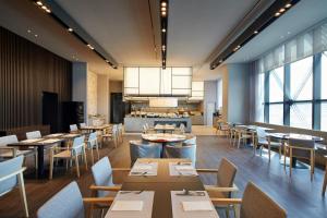 a restaurant with tables and chairs and a kitchen at Shilla Stay Seobusan Gimhae Airport in Busan