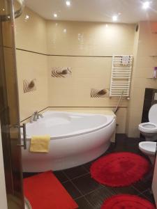 a bathroom with a tub and a toilet and red rugs at Rodzinny ,Luksusowy Apartament nad jeziorem w centrum Mragowa in Mrągowo