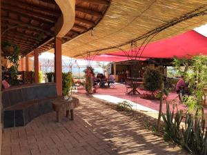 a patio with a bench and a red umbrella at Hotel SPA Campestre Los Adobes in Taxco de Alarcón