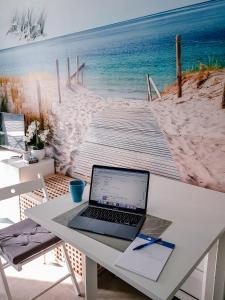 een laptop op een tafel naast een strand bij Studio Blue Cocoon Westende in Middelkerke