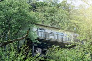 a house with a balcony in the middle of trees at 南熱海あじろハウス in Atami