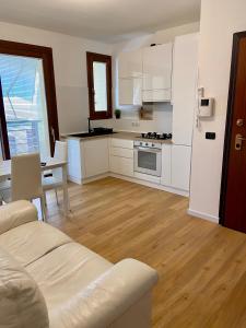 uma cozinha com armários brancos, uma mesa e um sofá em Ada's House em Alghero