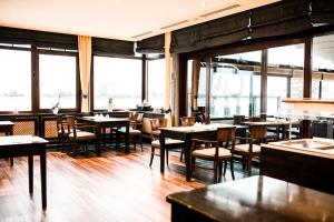 a dining room with tables and chairs and windows at Wiechmanns Weserhotel in Brake