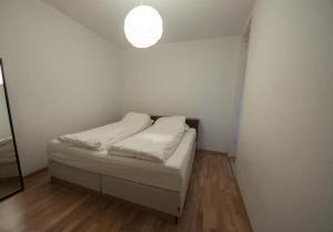 a small white bedroom with a bed and a light at Nice, Modern Apartment in Central Bergen in Bergen