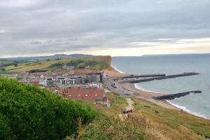 a town on a hill next to the ocean at Entire Ground Floor Apartment - West Bay in West Bay